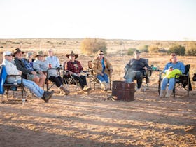 group of people sitting around a fire watching live music