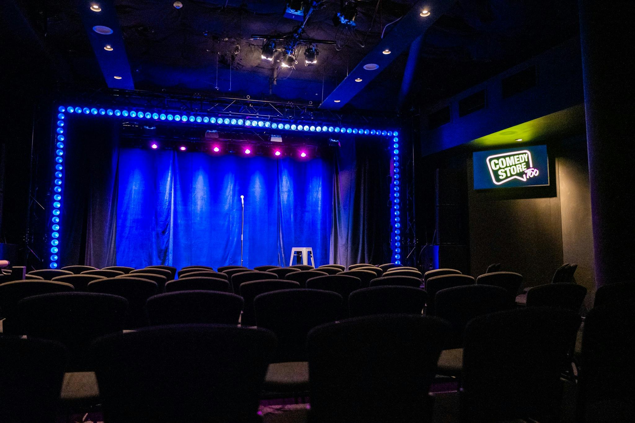 Interior of The Comedy Store theatre with empty stage and seating..