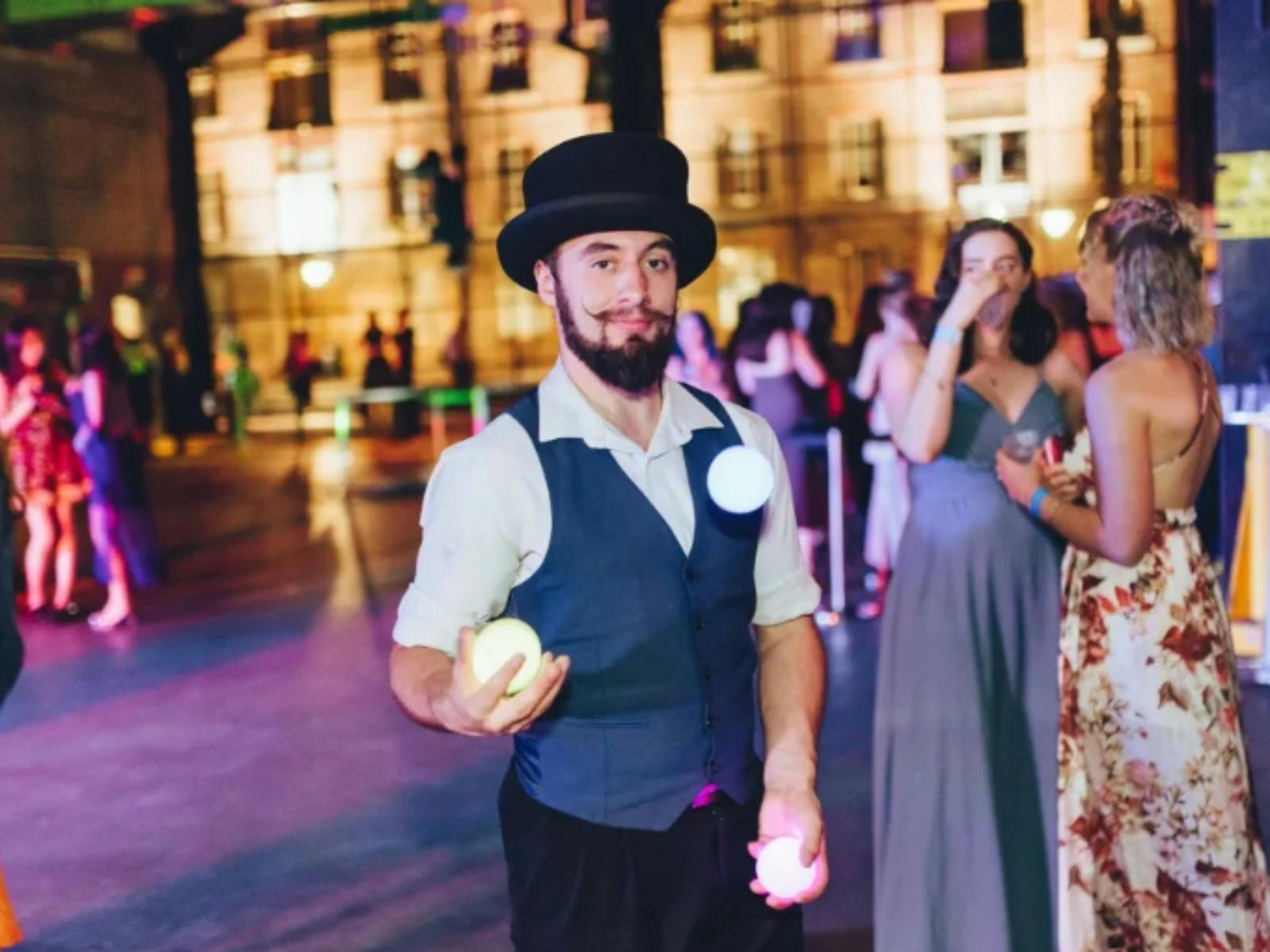 Circus performer wearing black top hat and juggling