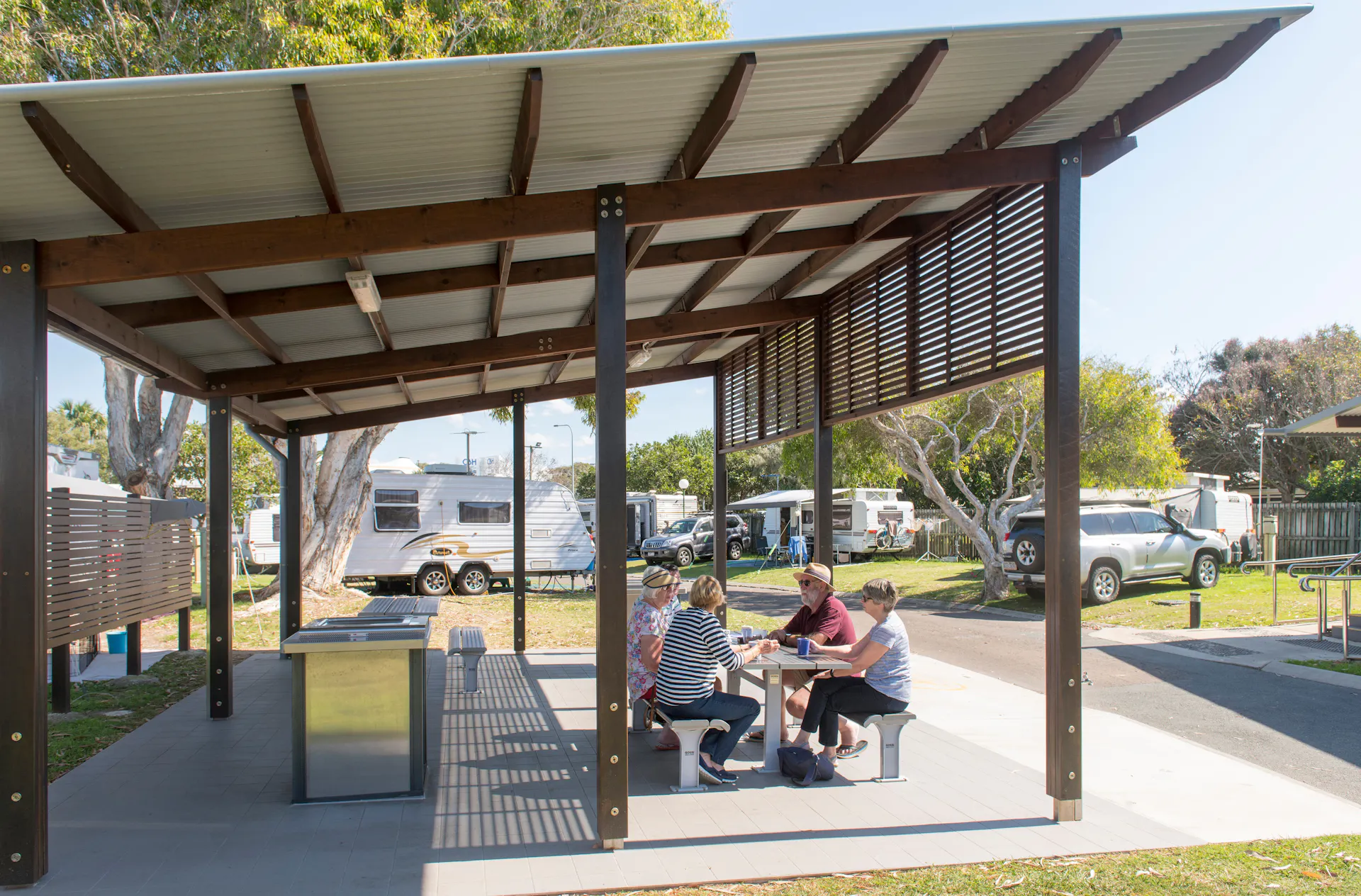 Image of Coolum Beach Holiday Park BBQ shelter with 3 women and 1 man sitting down at a table