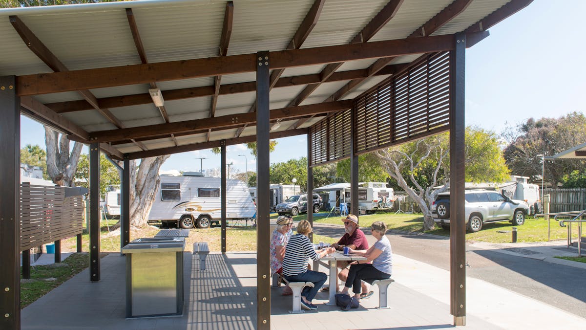 Image of Coolum Beach Holiday Park BBQ shelter with 3 women and 1 man sitting down at a table