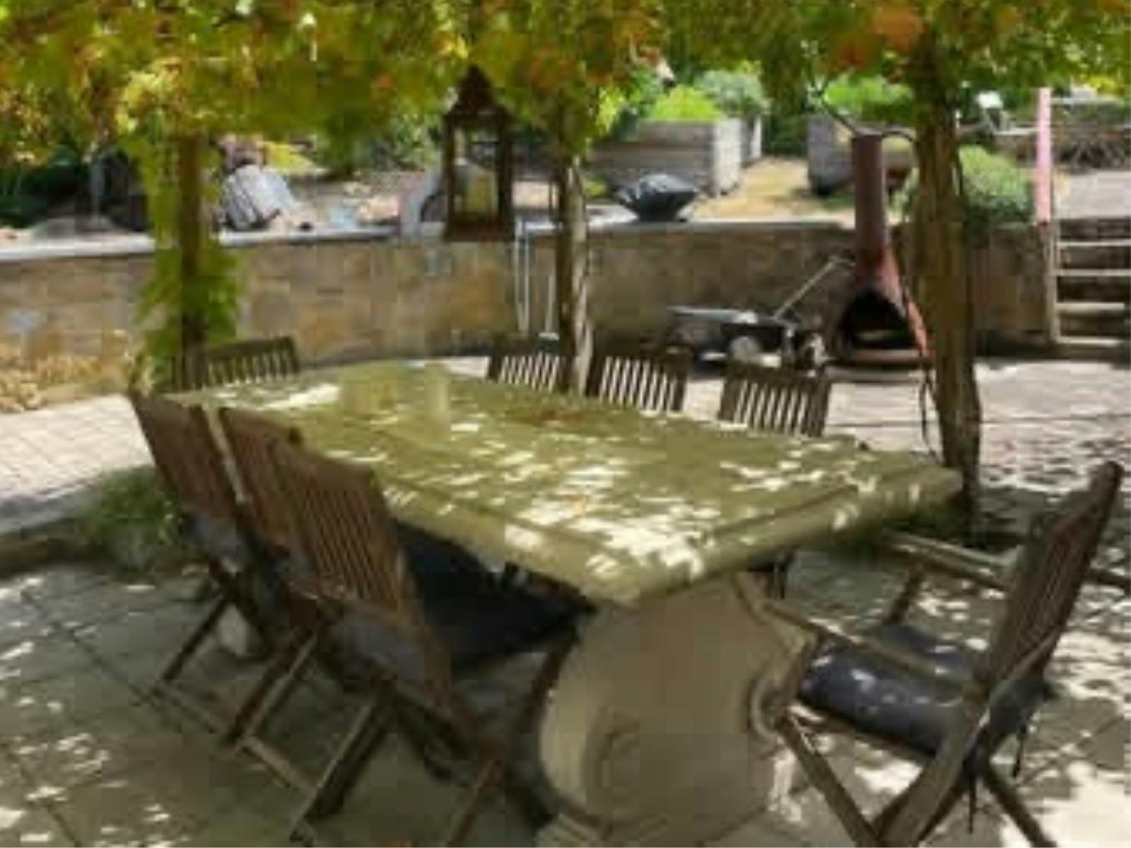 A courtyard with green trees, a pizza over and BBQ