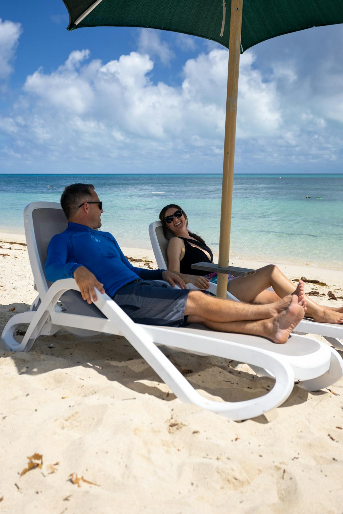 couple on beach chairs under an umbrella