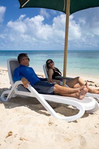 couple on beach chairs under an umbrella