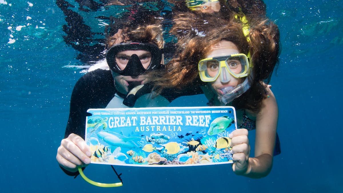 A couple pose for a photo on the Great Barrier Reef with Passions of Paradise