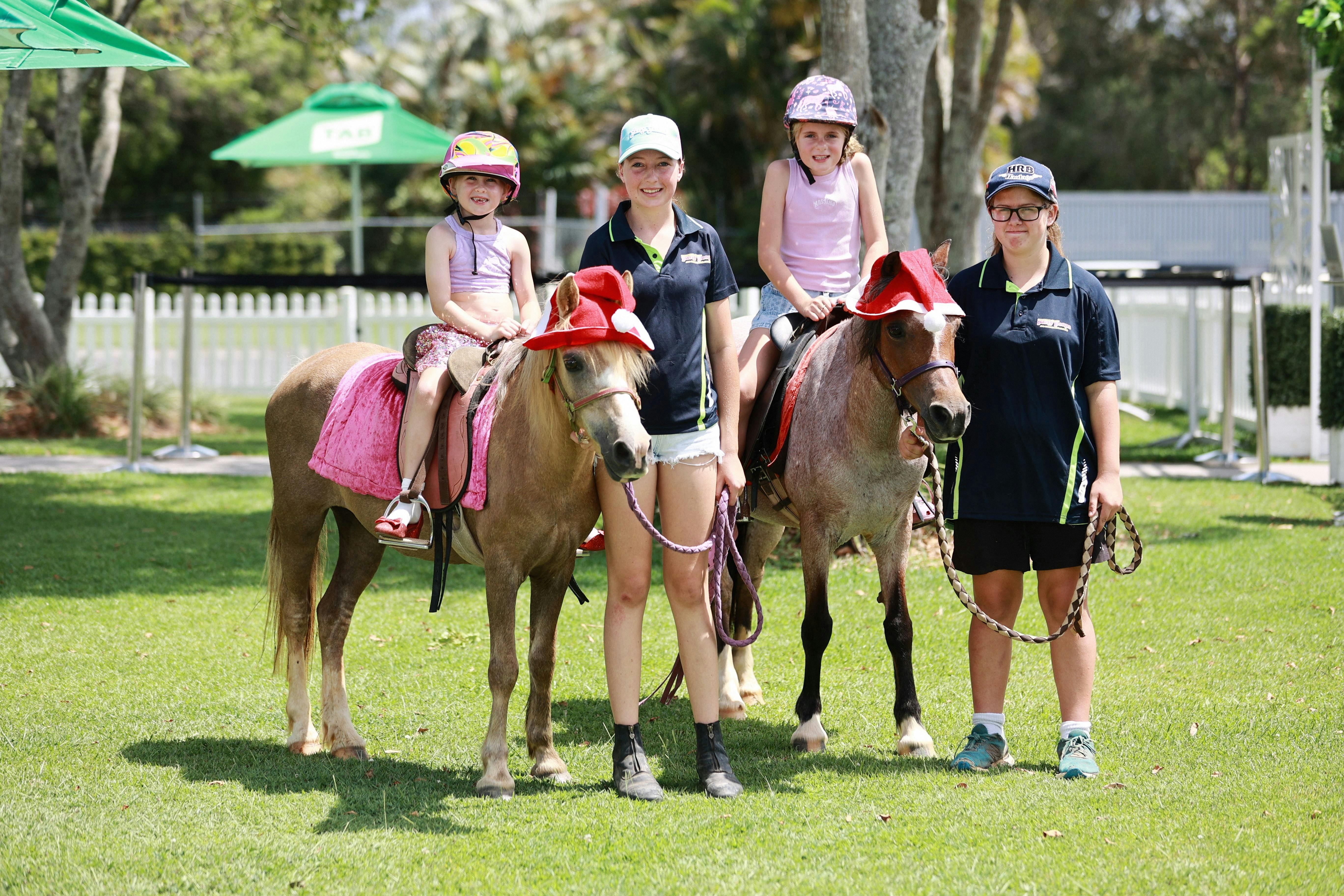 2 children riding ponies on the lawn