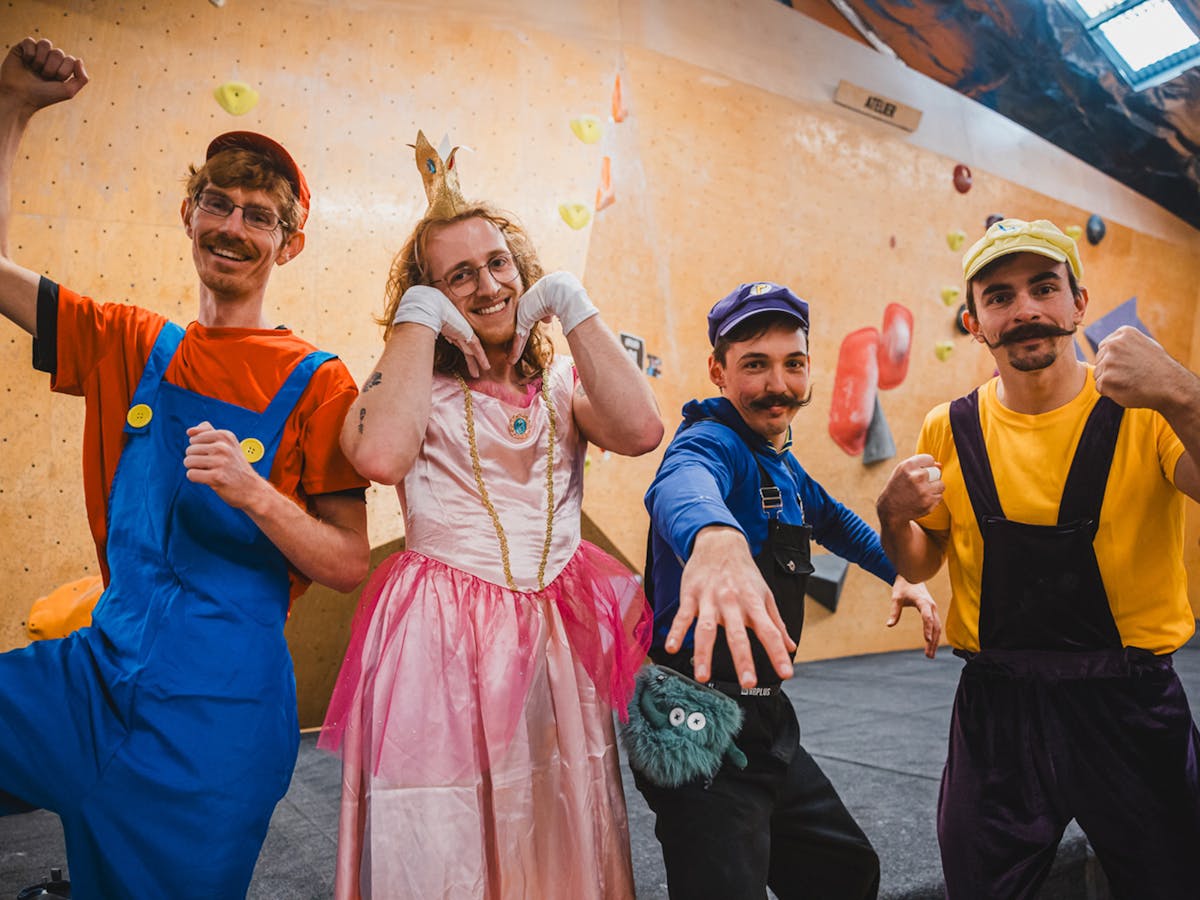 Four climbers pose in Super Mario Bros costumes, emulating fun and celebratory poses