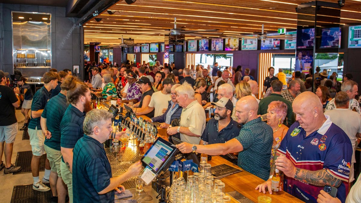 Crowded sports bar at The Pub, Airlie Beach Hotel, with multiple big screens and lively energy
