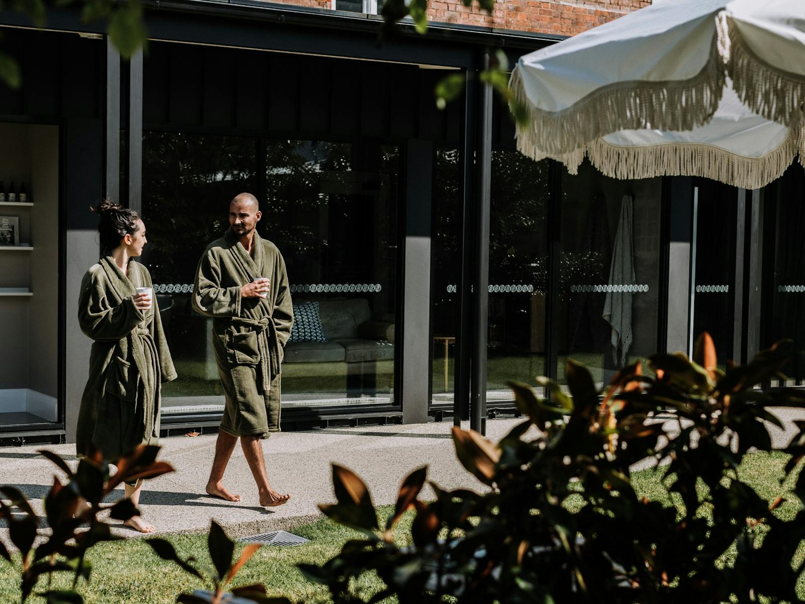 Couple walking outdoors in robes and with cup of hot beverage