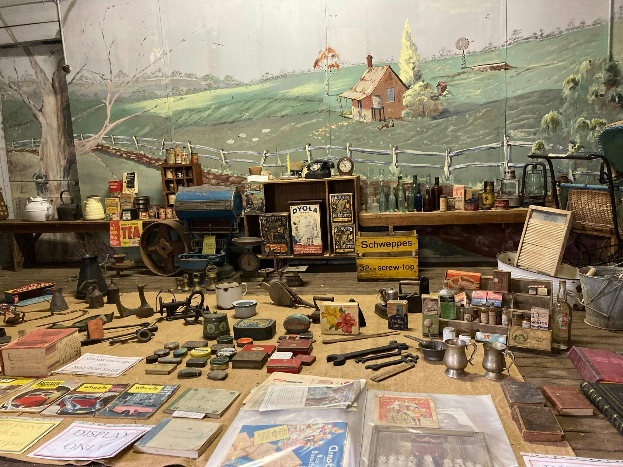 A stage with paddock scenery backdrop; historical books and household items in the foreground