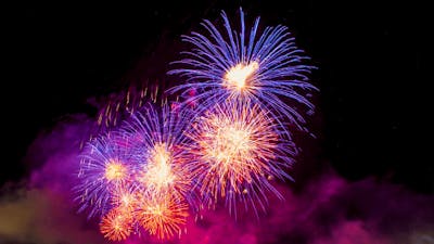 Fireworks bursting with purple and pink colours in in the night sky