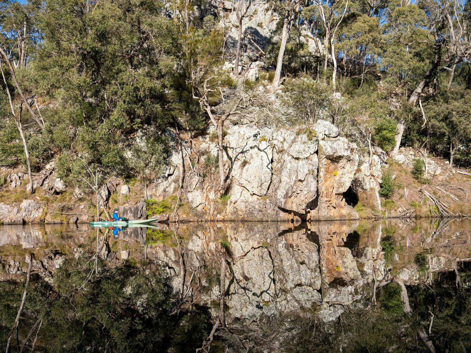 Kayak guide David reflected in Brogo Dam water, rock and tree reflections.