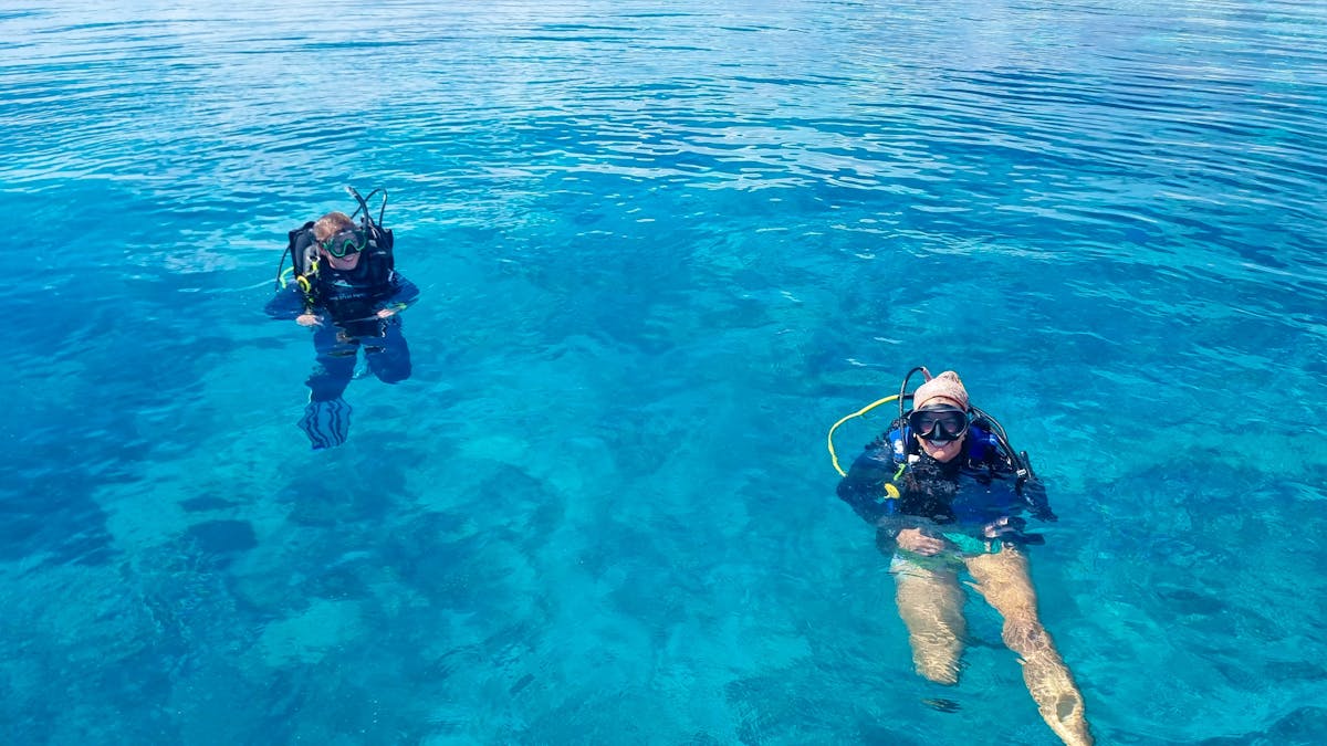 Two Divers ready to descend into turquoise water