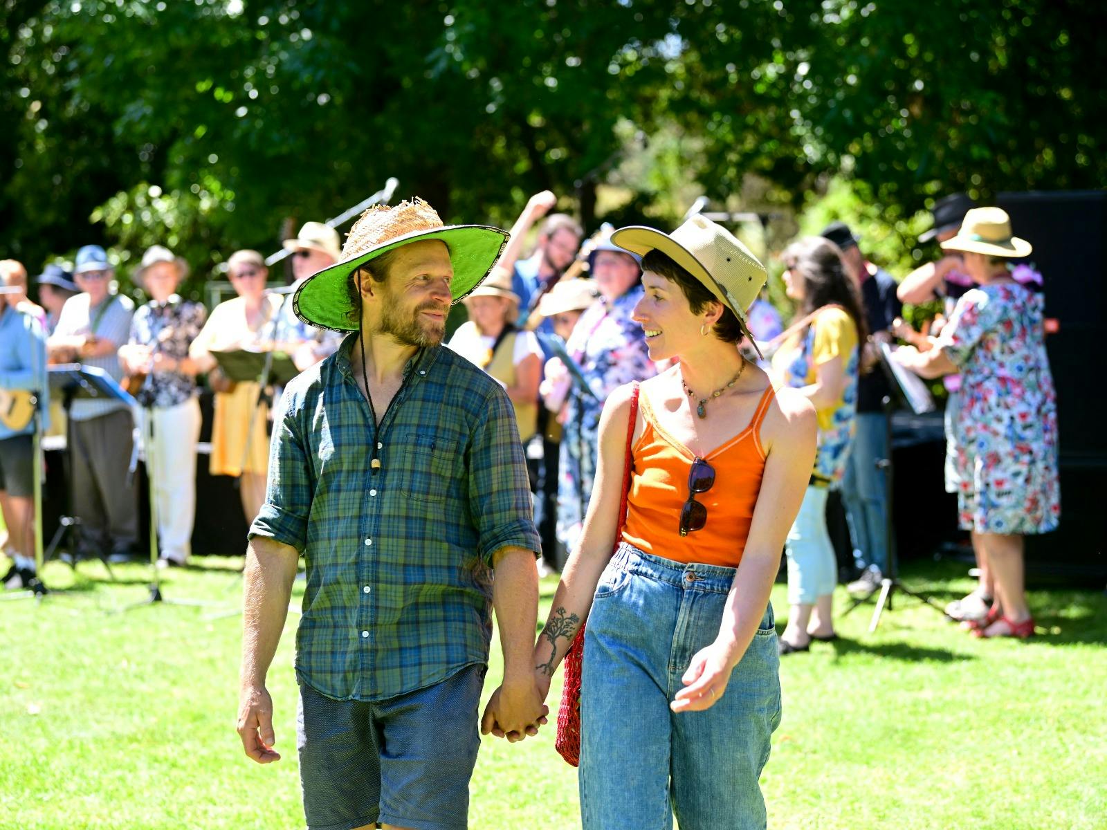 A man and a woman holding hands, looking at each other while walking
