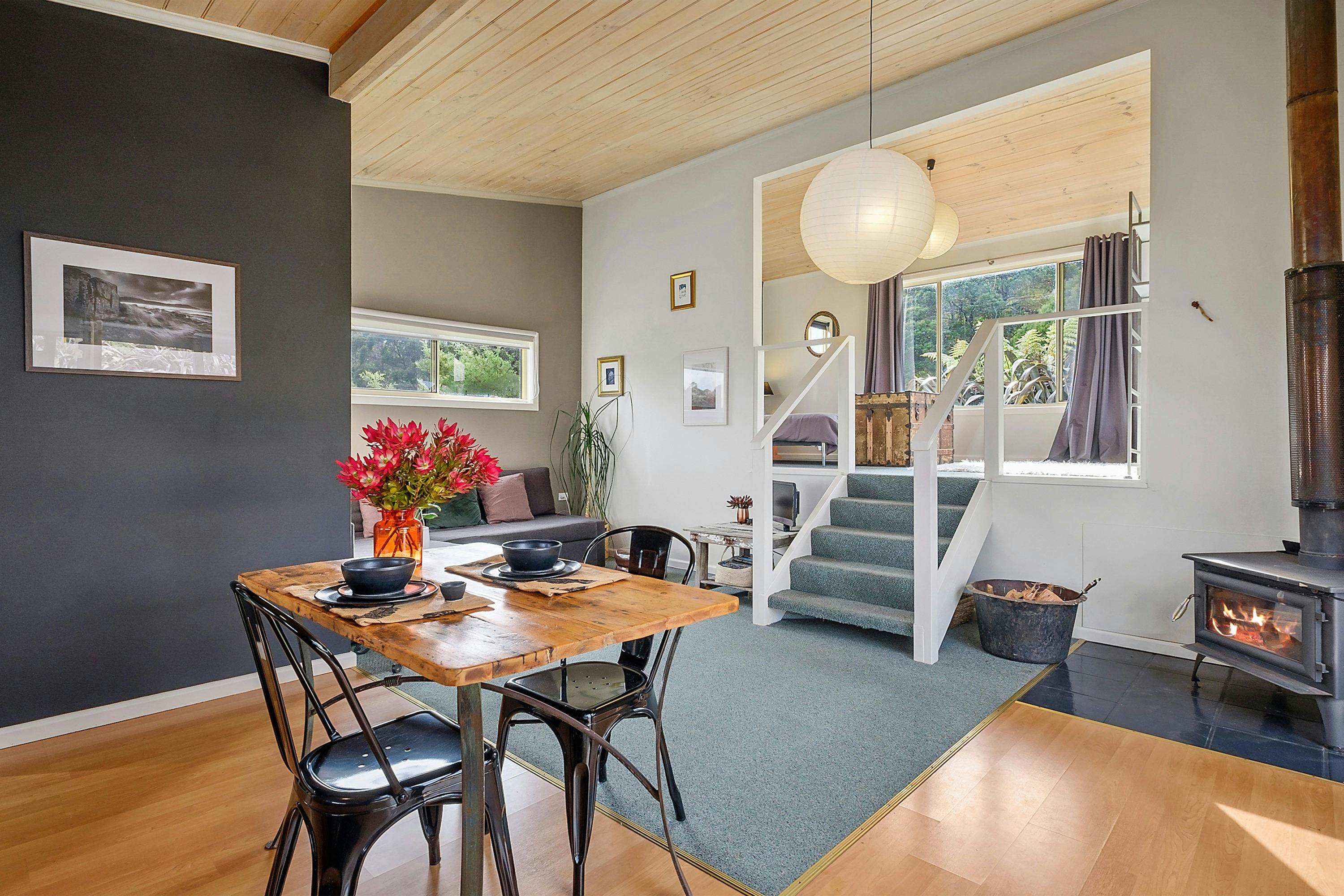 The Bath Hideaway dining/lounge area, staircase to bedroom and wood stove