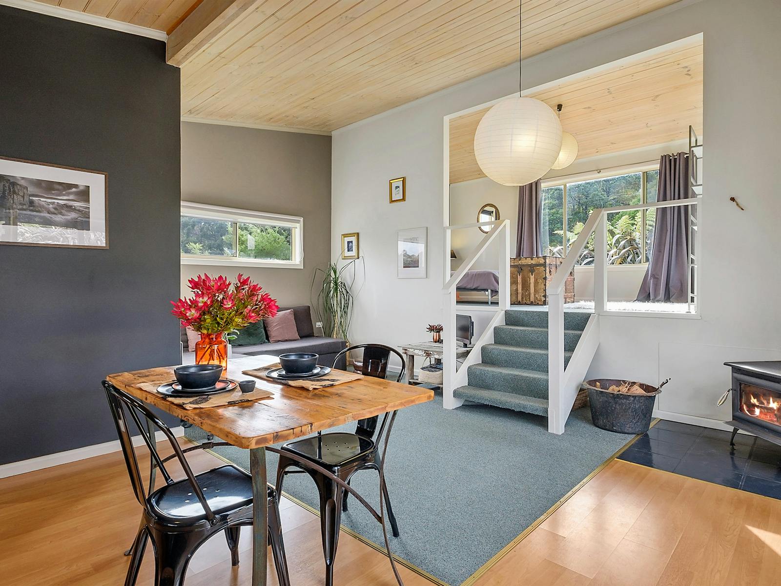 The Bath Hideaway dining/lounge area, staircase to bedroom and wood stove