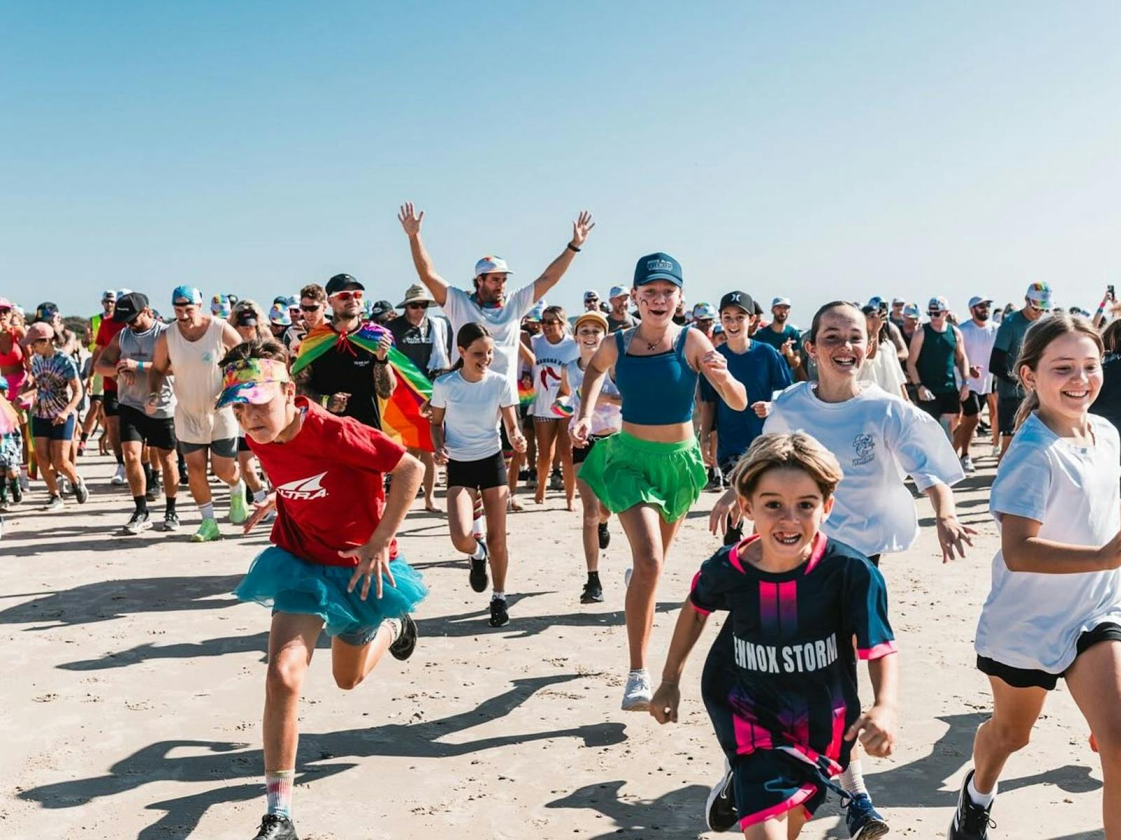 Crowd of people running along the beach