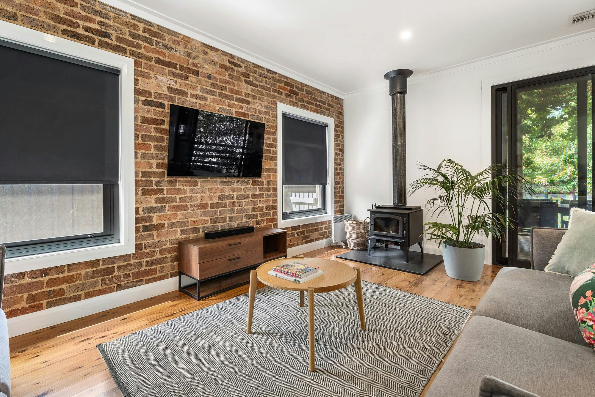 Lounge room with fireplace, television, rug, brick feature wall