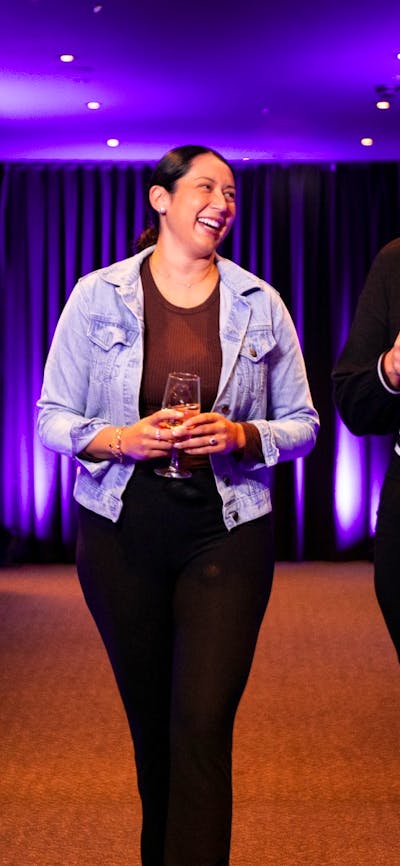 Two women walking down a hallway holding wine and laughing