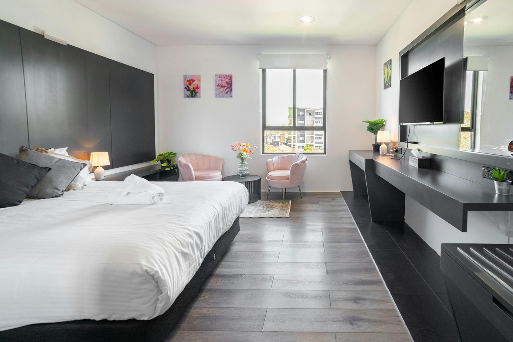 Modern deluxe motel room with a king bed, seating area, smart TV, workspace, and large window at Mot