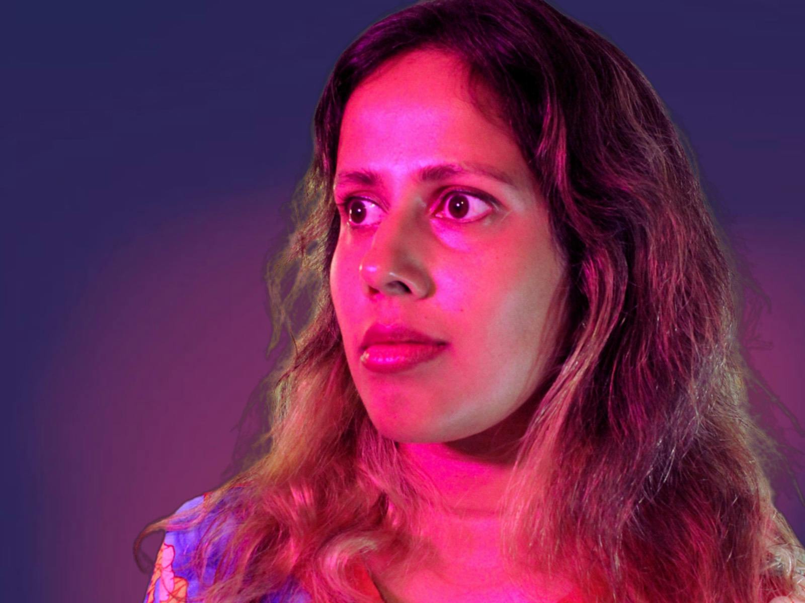 Young woman with a neutral face under bright pink lights