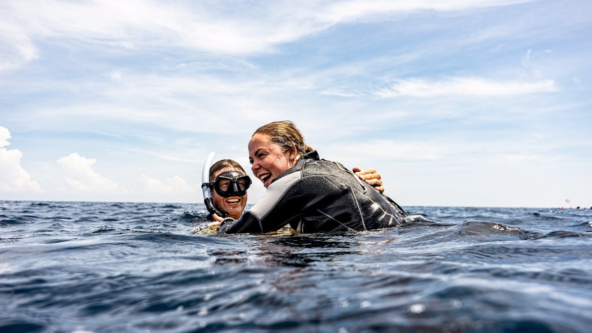 An instructor and freediving resting at the safety buoy after the diver came up from the line