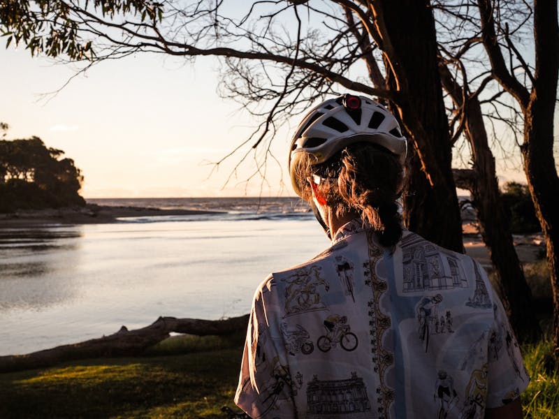 Female cyclist watching the sunset over the water
