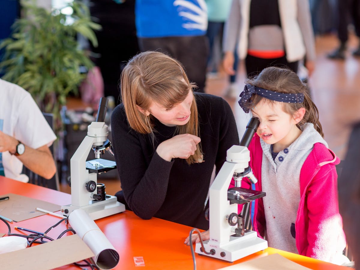 An adult and a child looking through a microscope