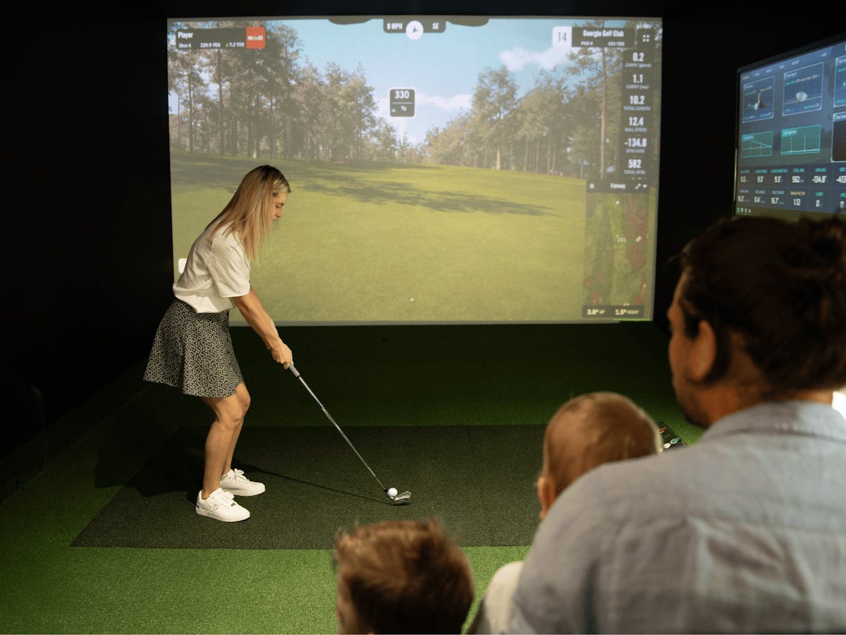 A young family enjoys the golf simulator. A young family enjoys the golf simulator.