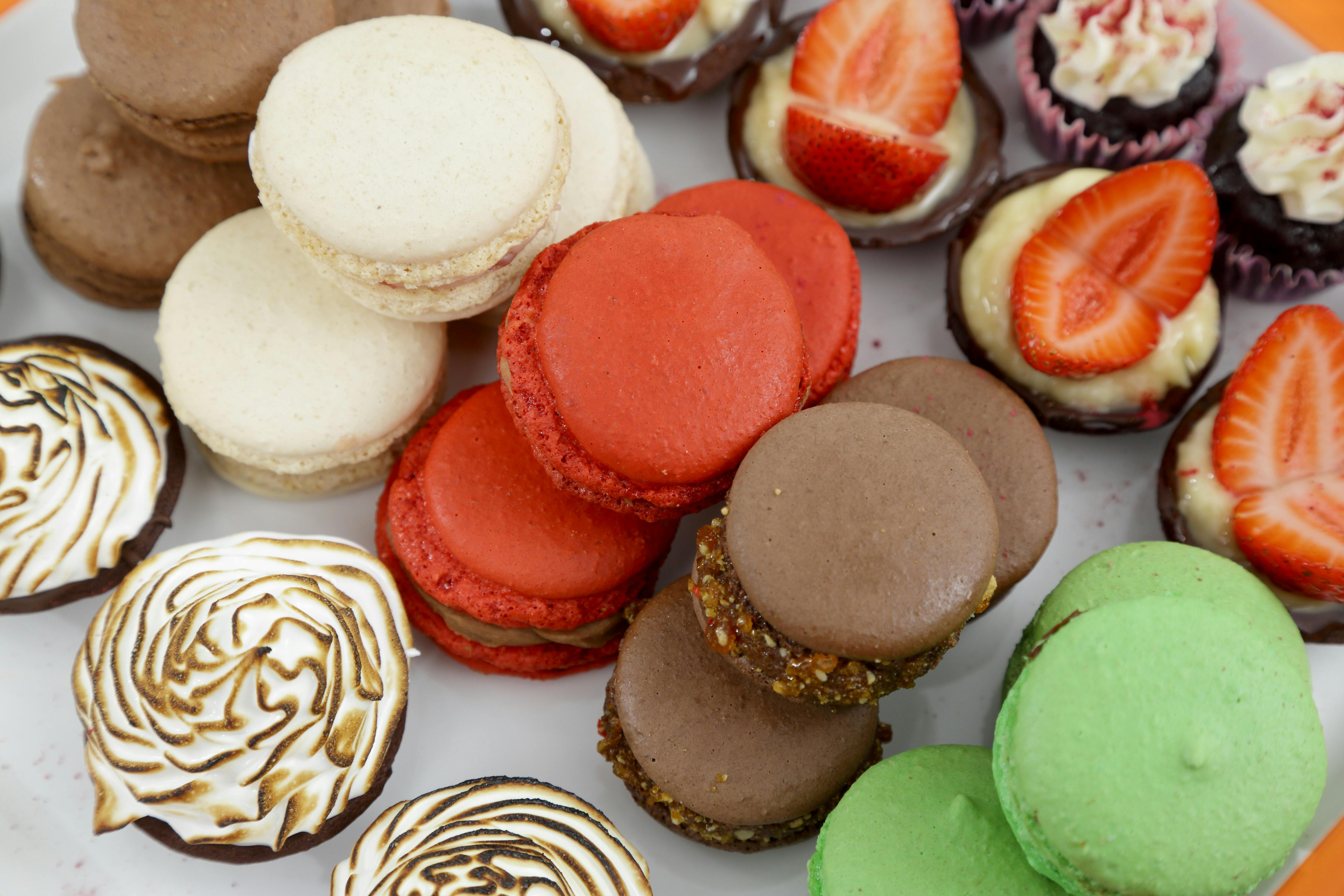 White, red, brown and green macaron and small cakes on a plate in Jacican cooking school, Gippsland