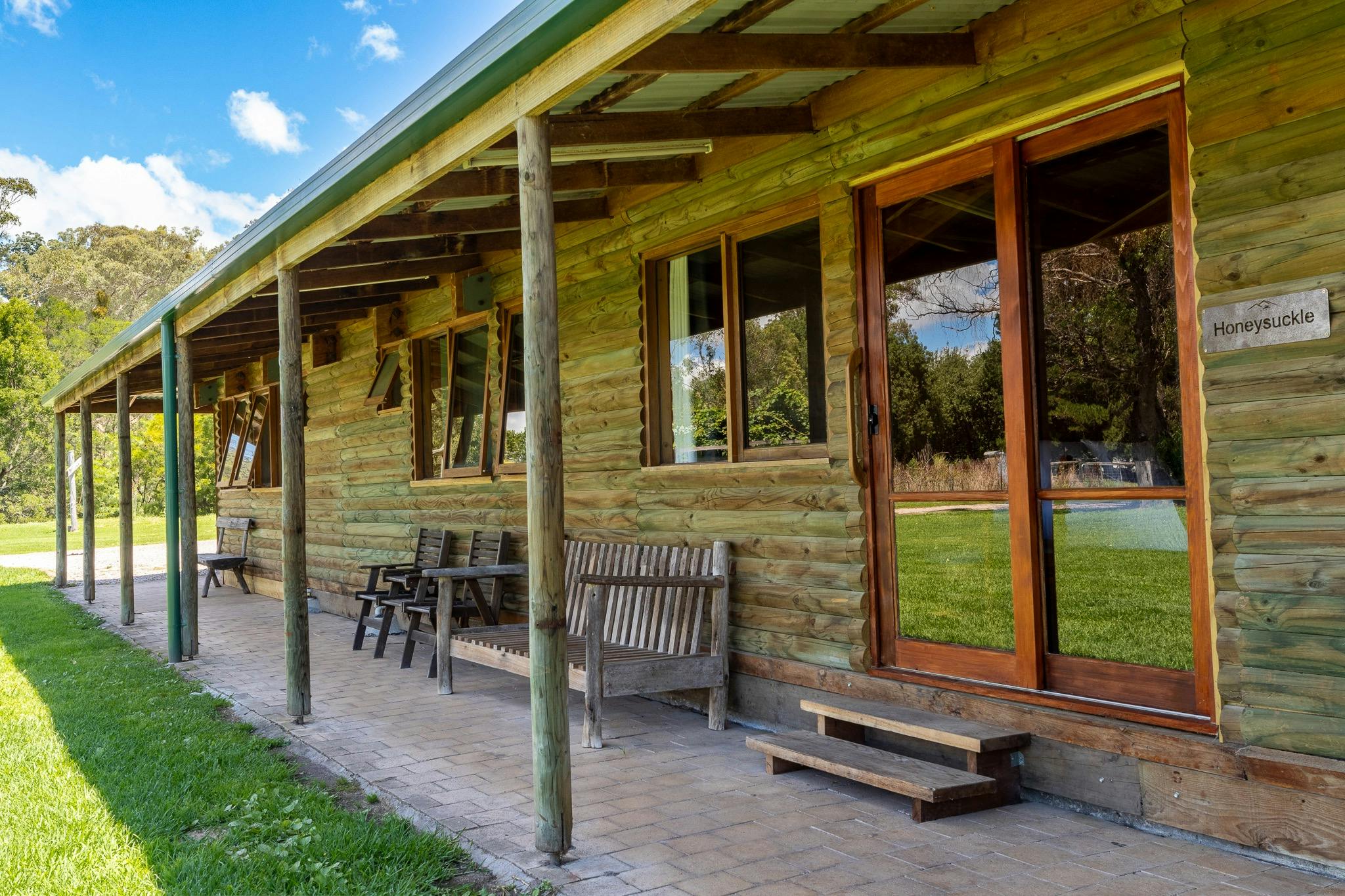 exterior of a wooden cabin with wooden chairs and benches outside