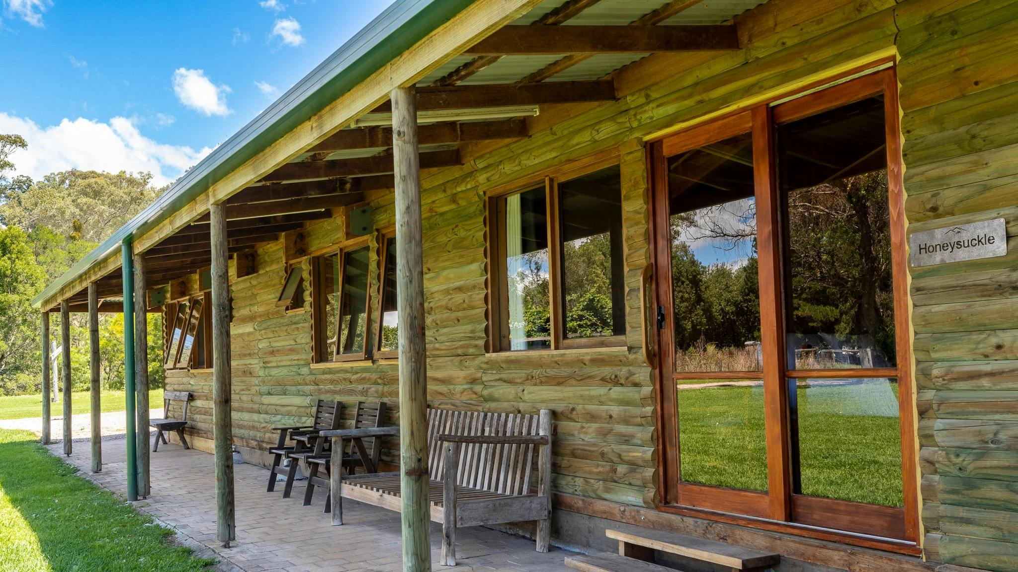 exterior of a wooden cabin with wooden chairs and benches outside