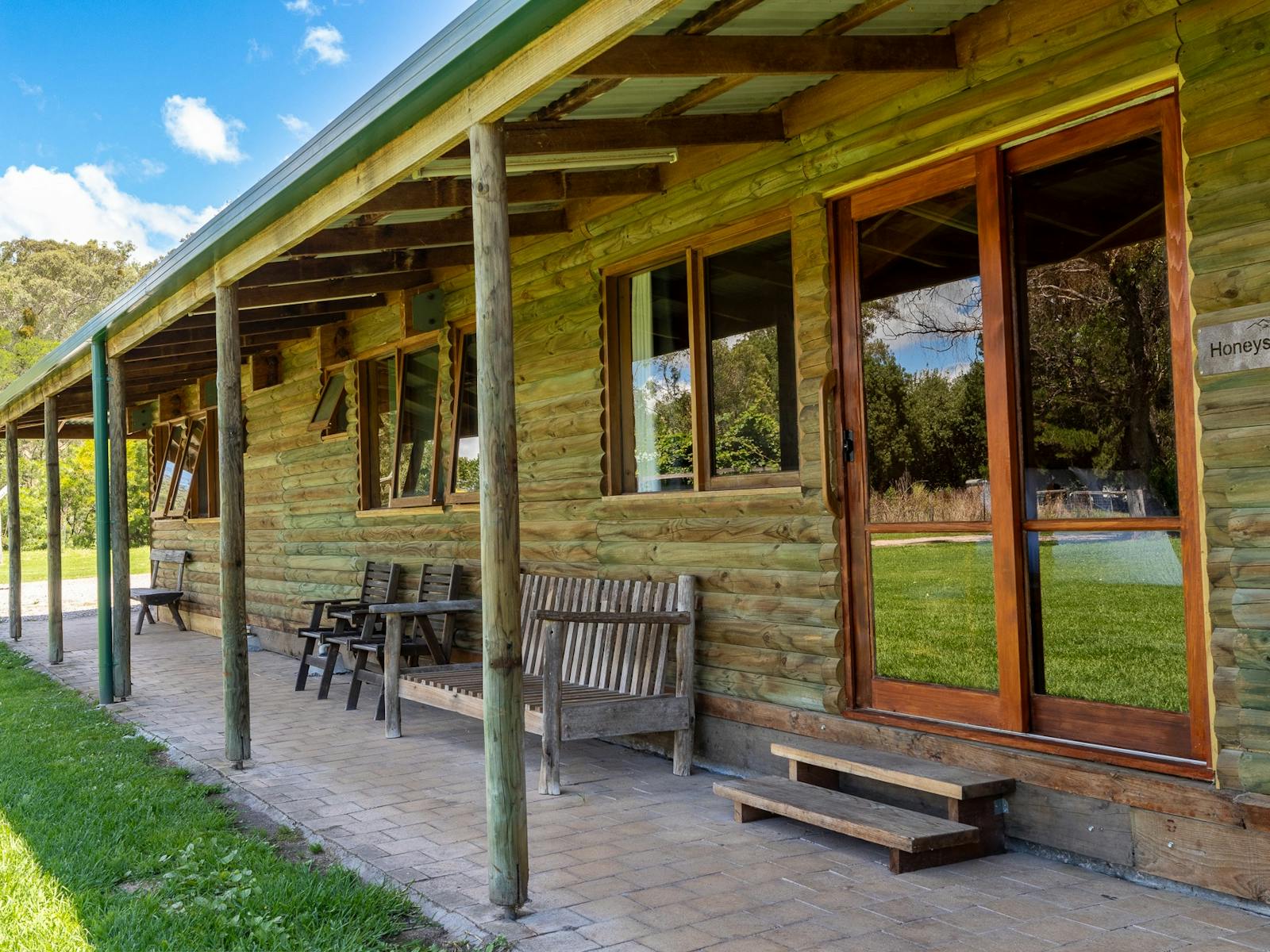 exterior of a wooden cabin with wooden chairs and benches outside