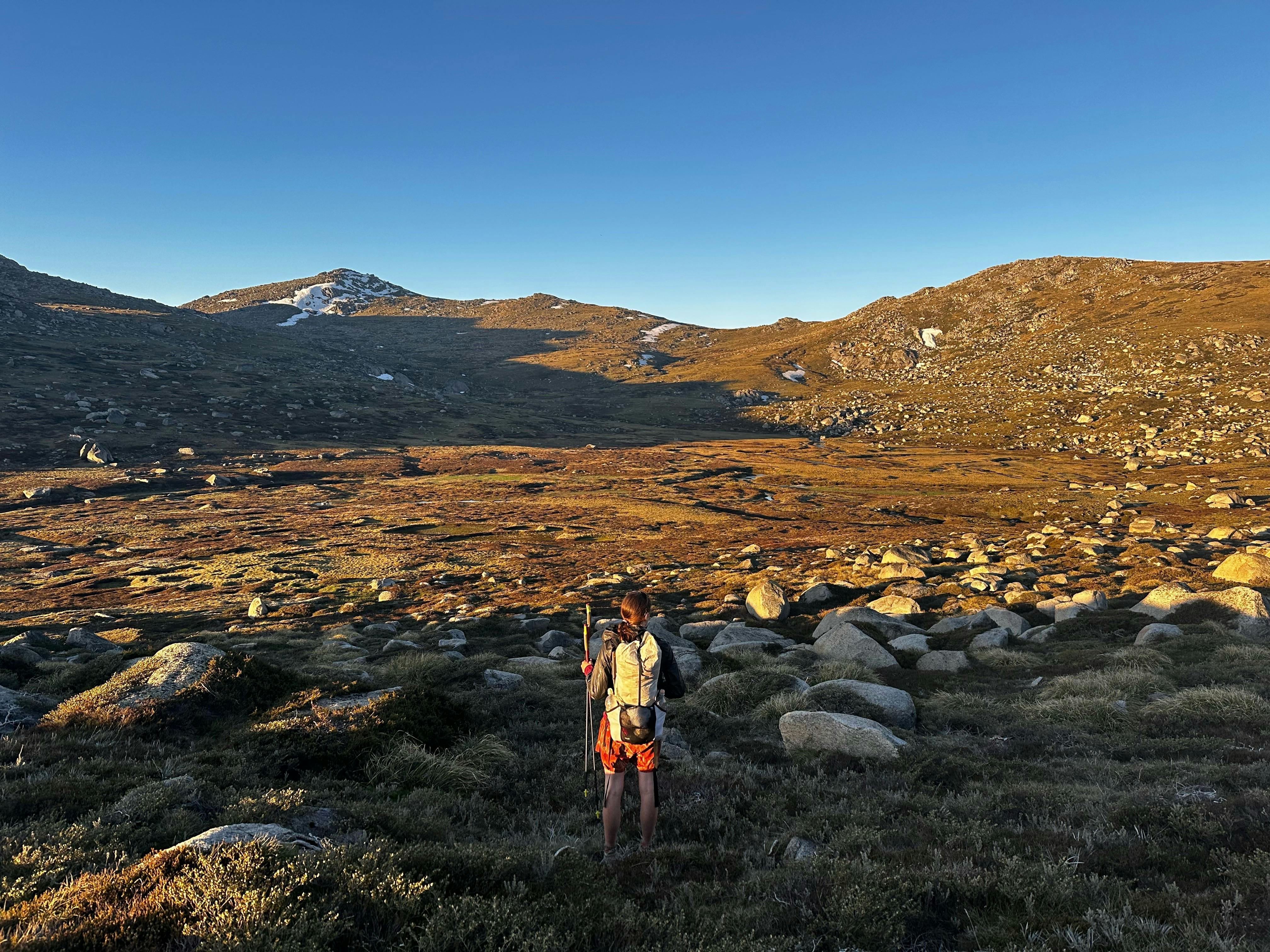 A hiker looking out into a valley in the mountains.