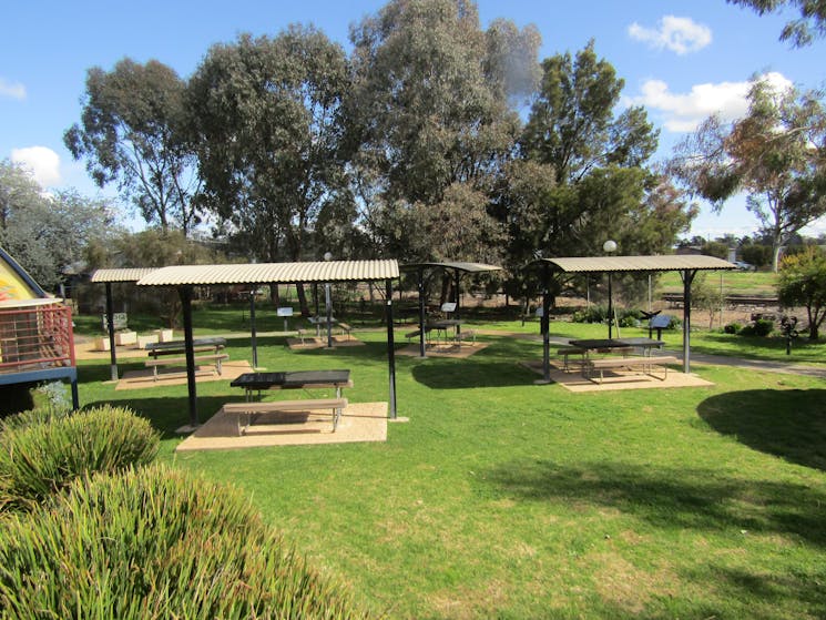 Lawned area with picnic shelters surrounded by shrubs and gum trees