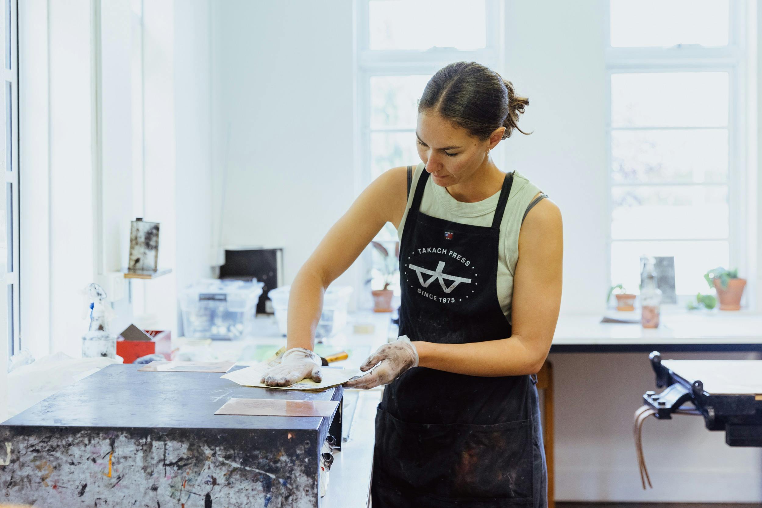 A woman prepares an etching using inks and paper