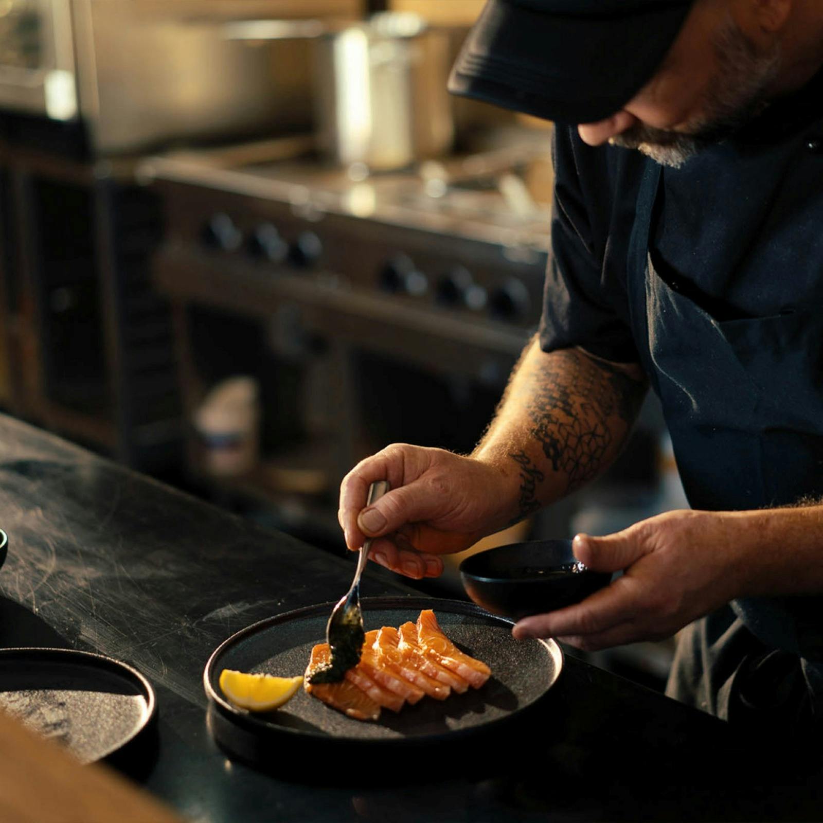 A chef carefully plating up salmon and caviar