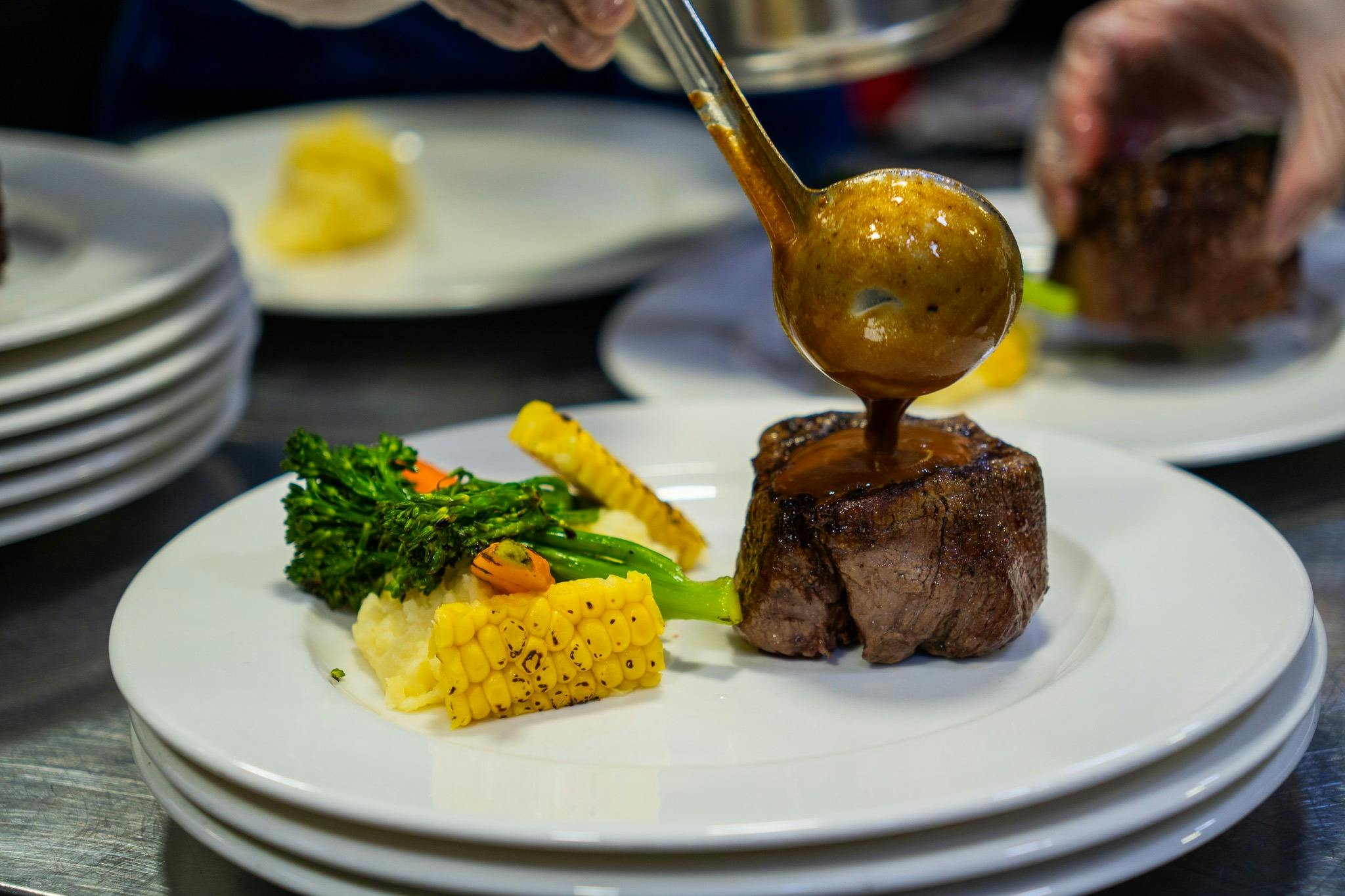 chef pouring sauce on another meal option for cruise