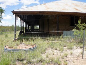 General view of the original Telegraph Station building, showing badly deteriorating woven bamboo slat screening to verandah and missing sections of low corrugated iron wall to perimeter of  building.