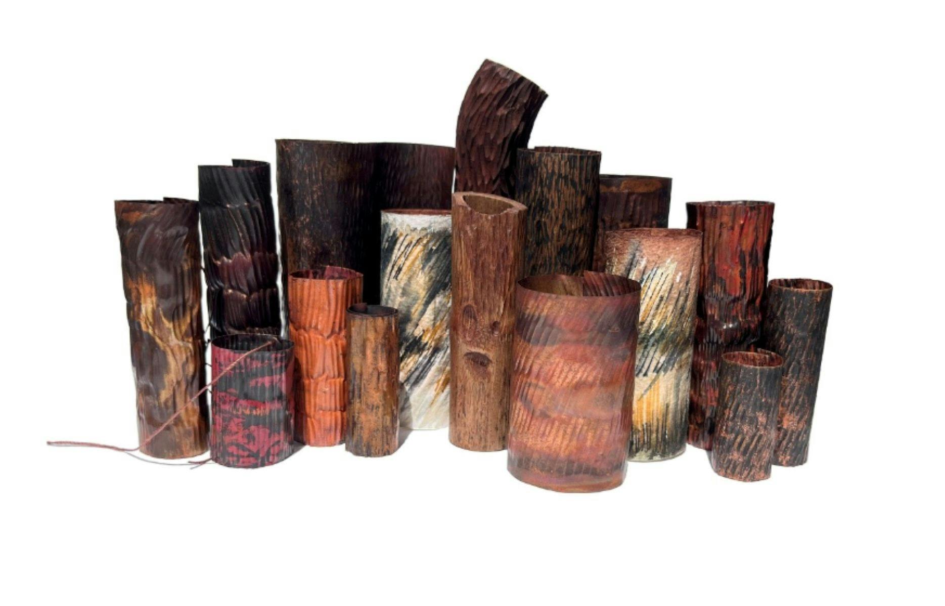 A collection of earthen coloured metal vessels against a white background