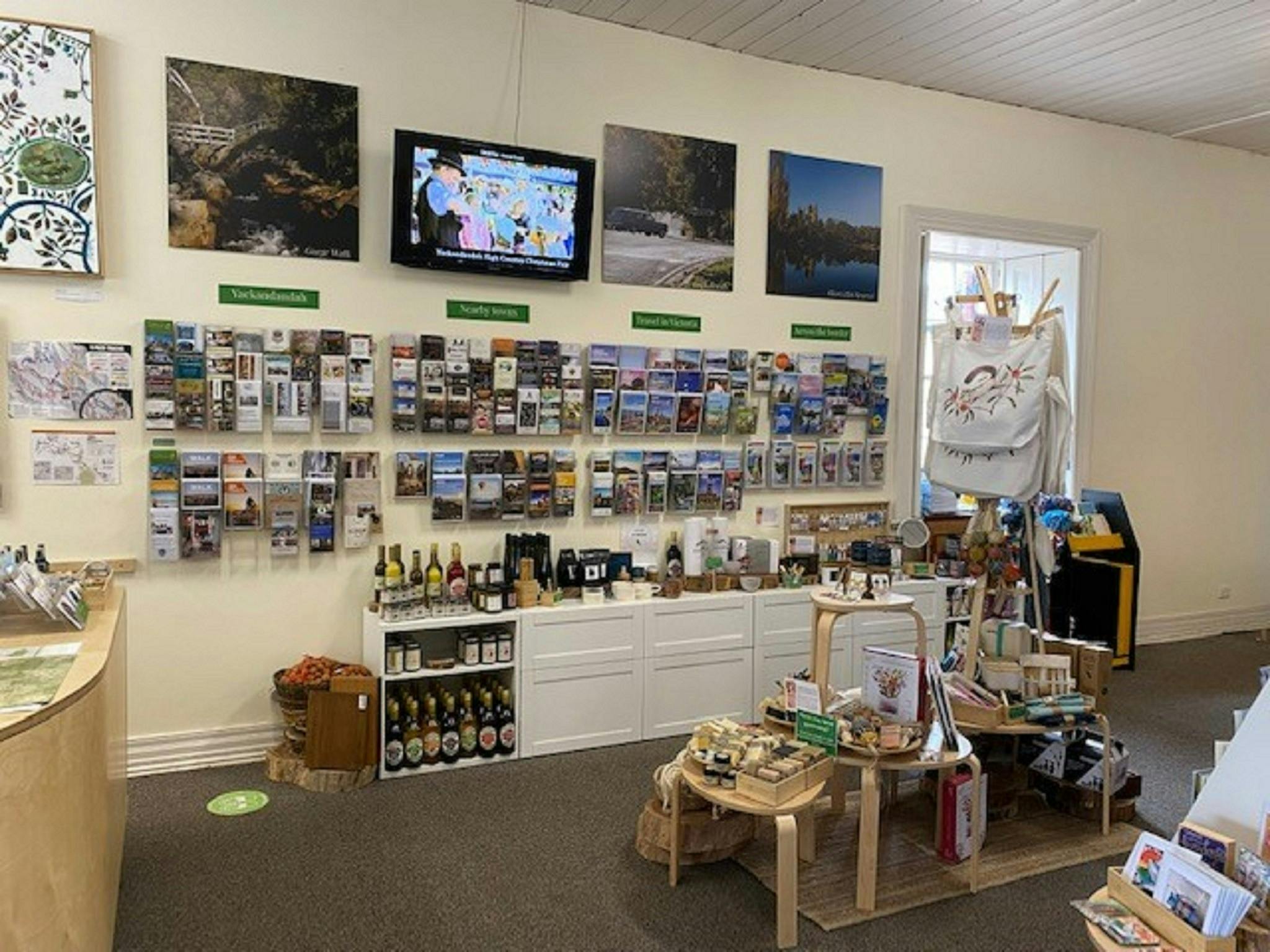 Brochure wall with souvenirs and local produce and products displayed on white cabinet