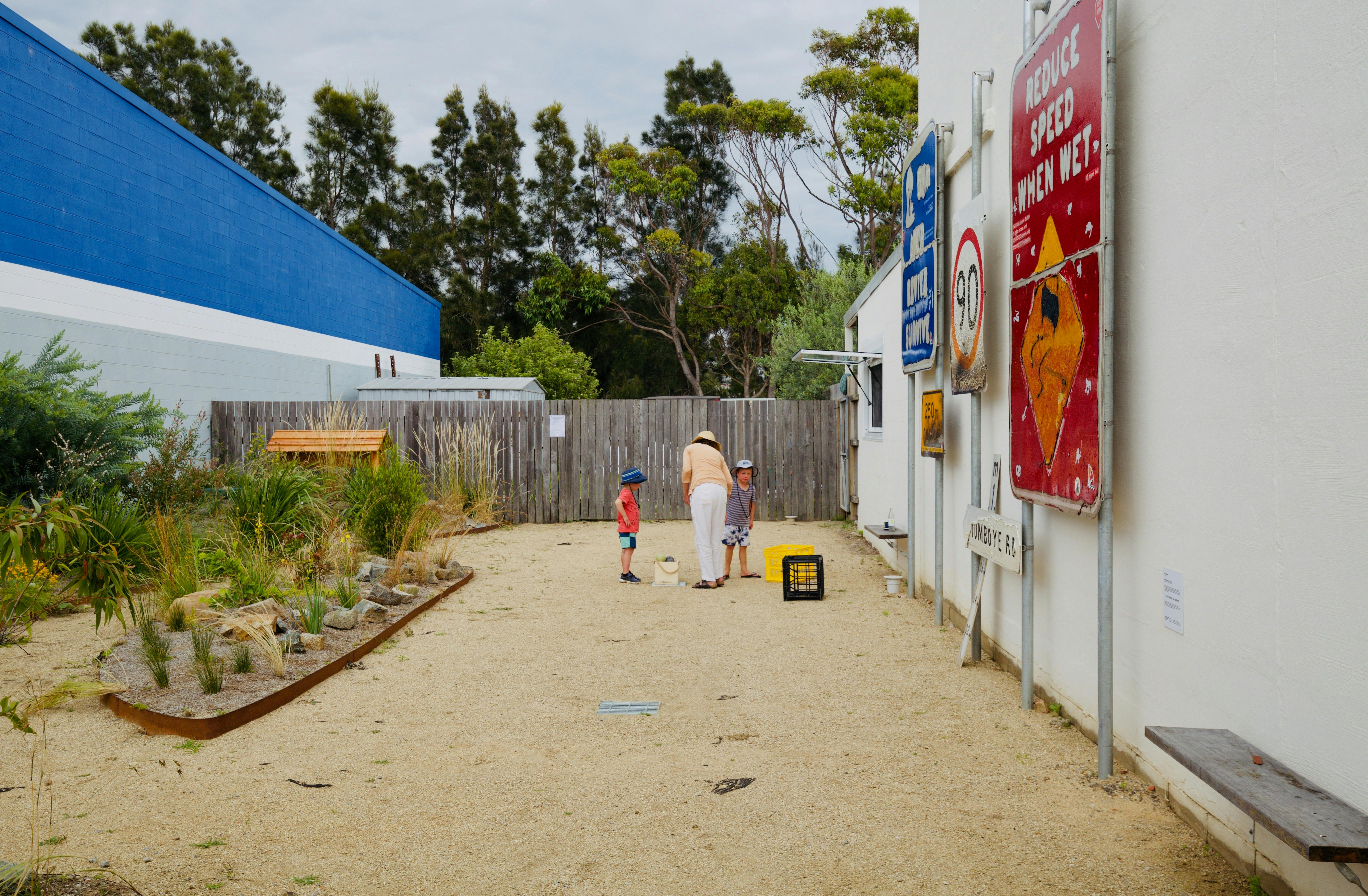 A woman and two children playing Bocce in the courtyard