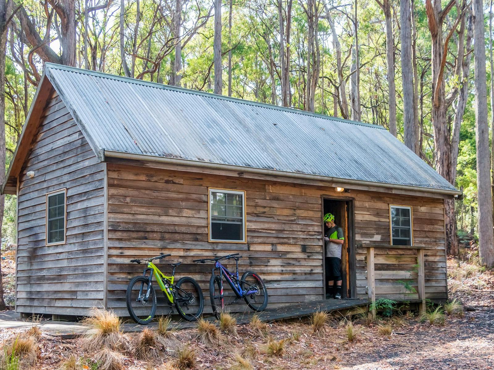 Troy Brosnan standing in the doorway of the Settlers Hut with MTB bikes