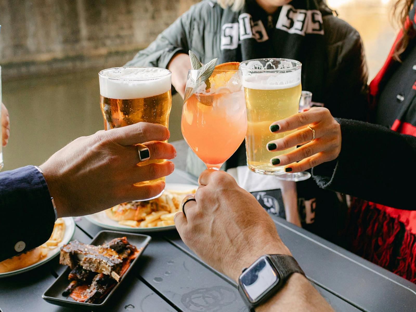 Sports fans cheersing drinks with Yarra River in background.
