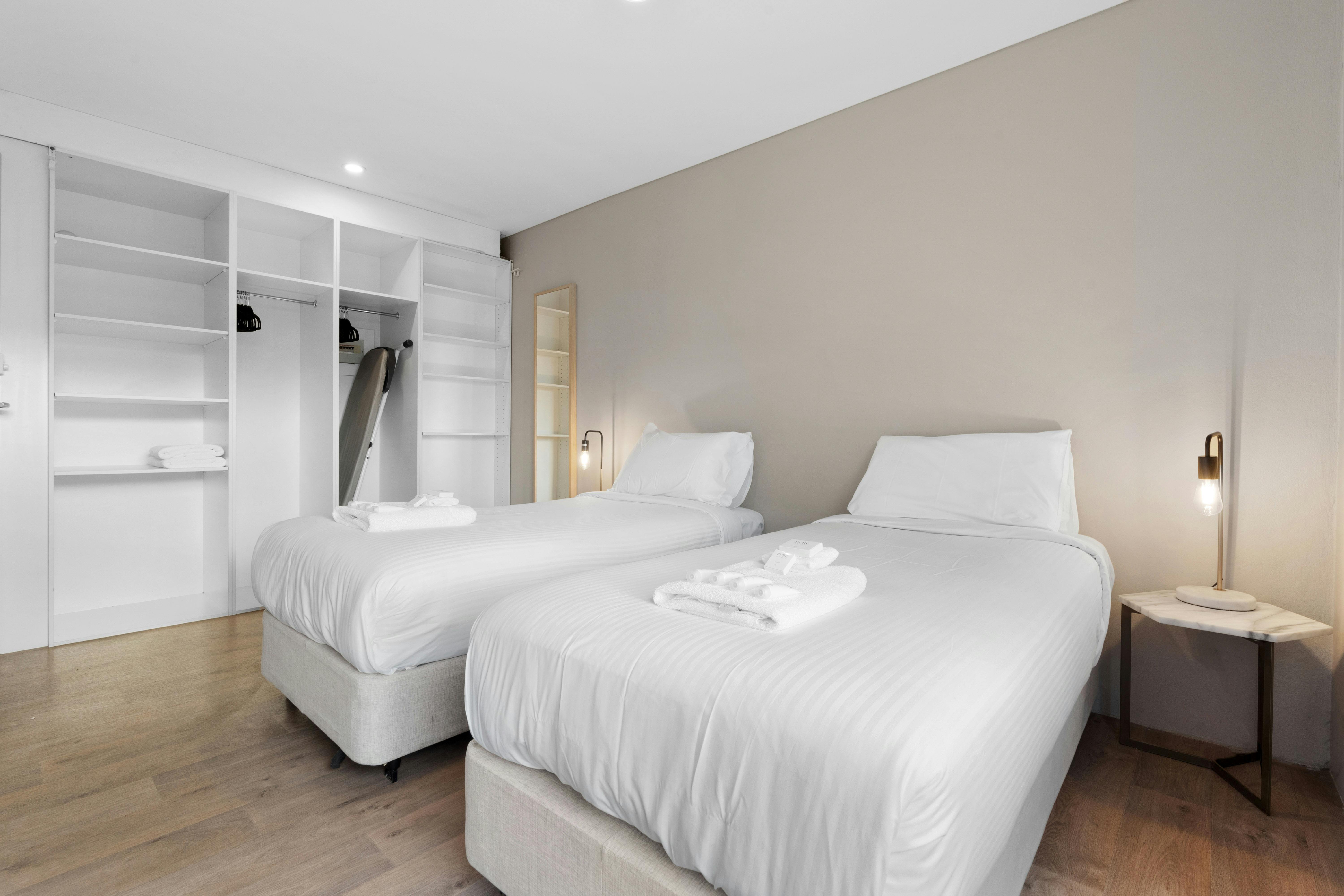 舒適的臥室配有兩張床、大衣櫃和柔和的燈光。