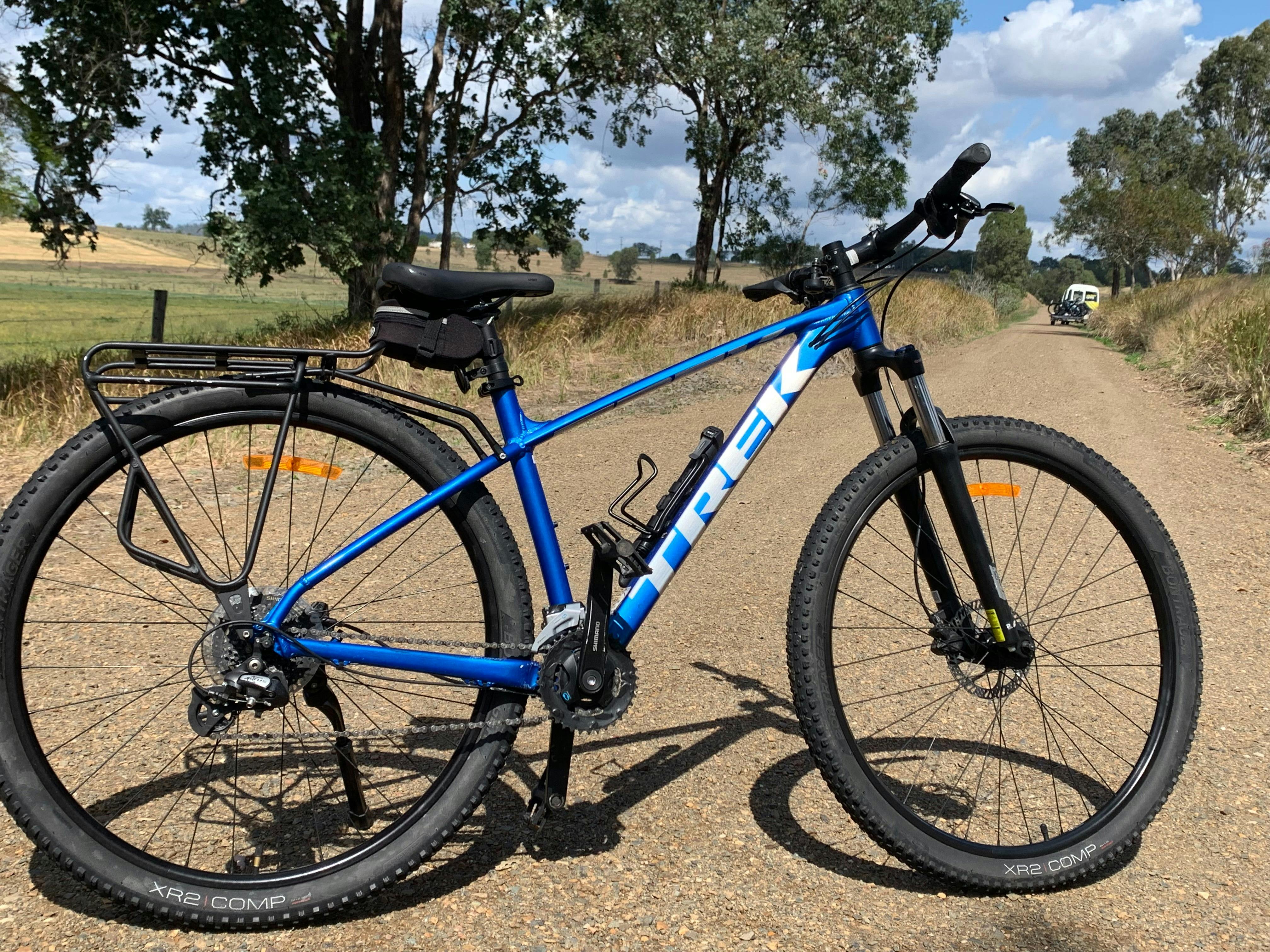 blue hardtail mountain bike with the rail trail behind it