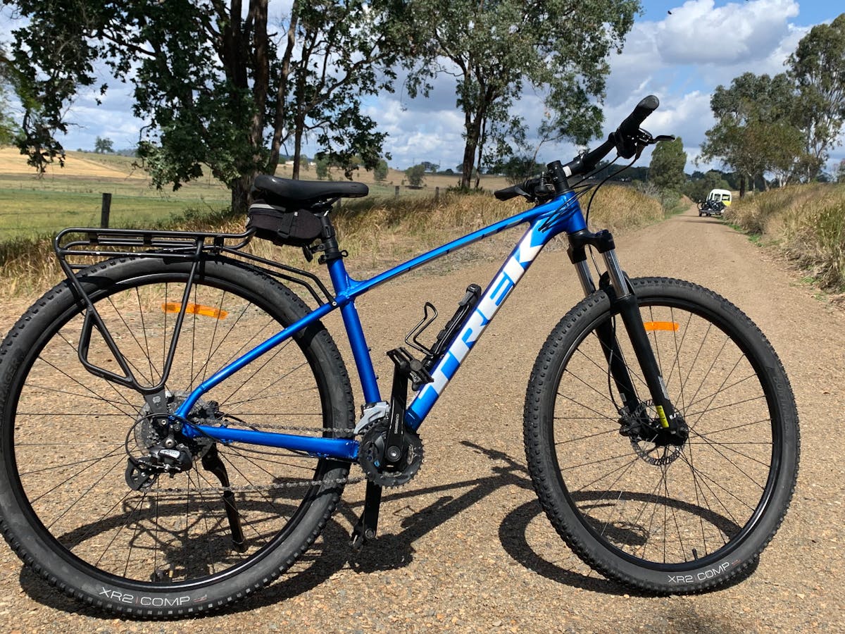 blue hardtail mountain bike with the rail trail behind it
