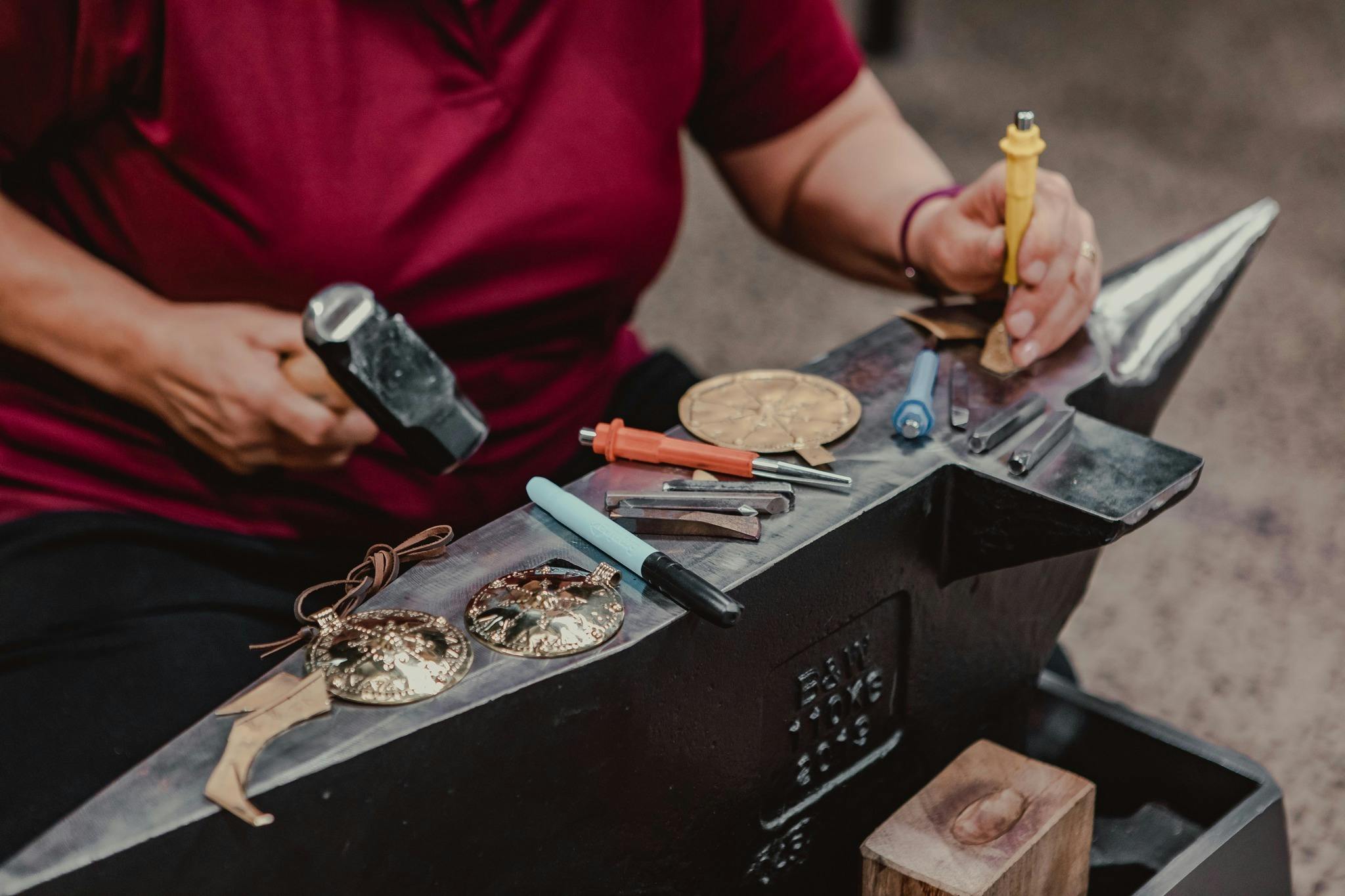 Close up of hands working with metal on anvil