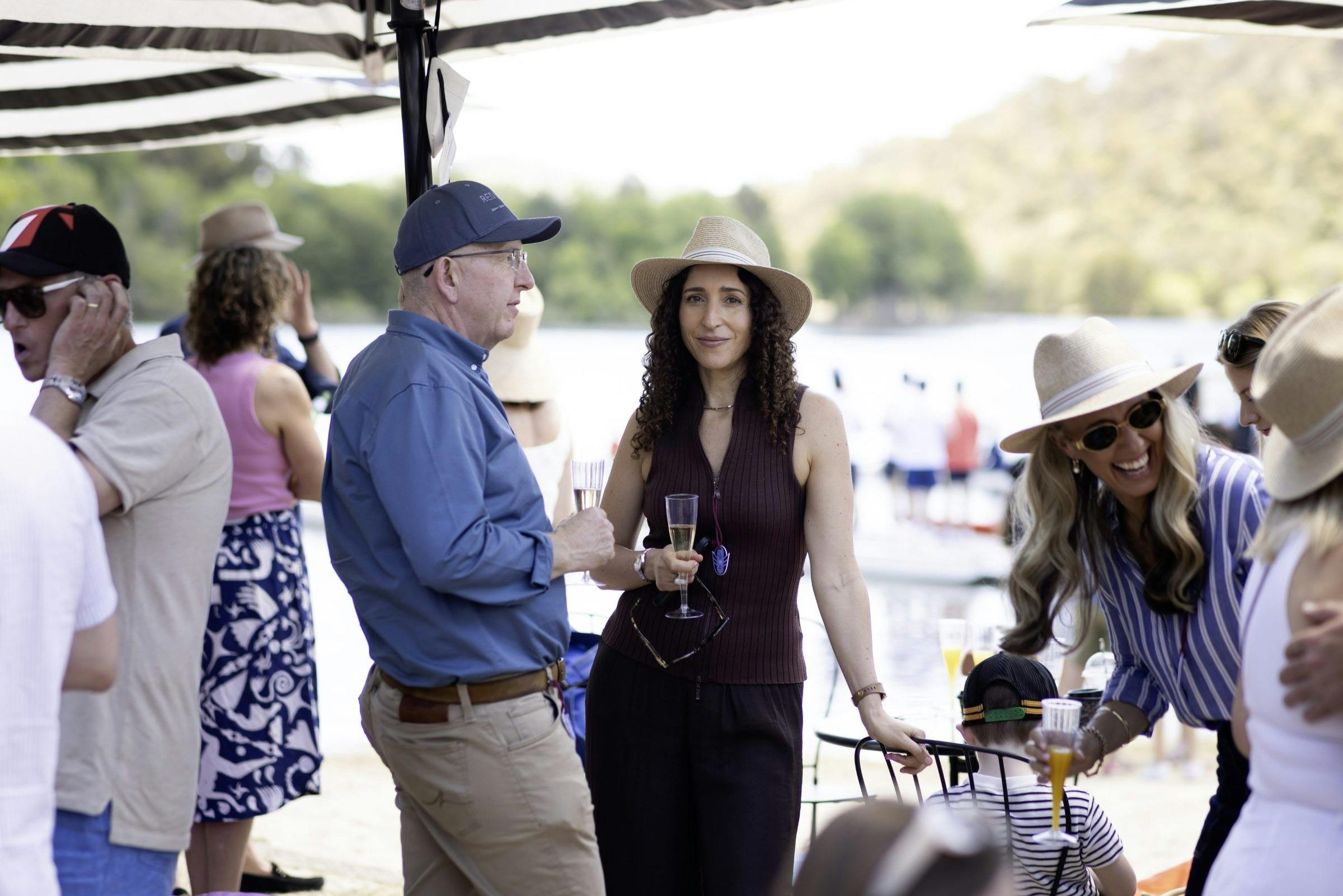 Spectators with drinks standing by the lake watching the racing
