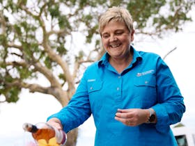 Coonawarra Experiences Smiling woman pouring rosu00e9 wine outdoors during a hosted experience.